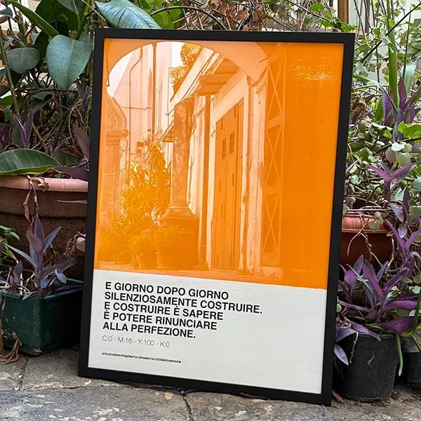Costruire, Niccolò Fabi – orange Opera Poster with the line «E giorno dopo giorno silenziosamente costruire», black frame, among plants